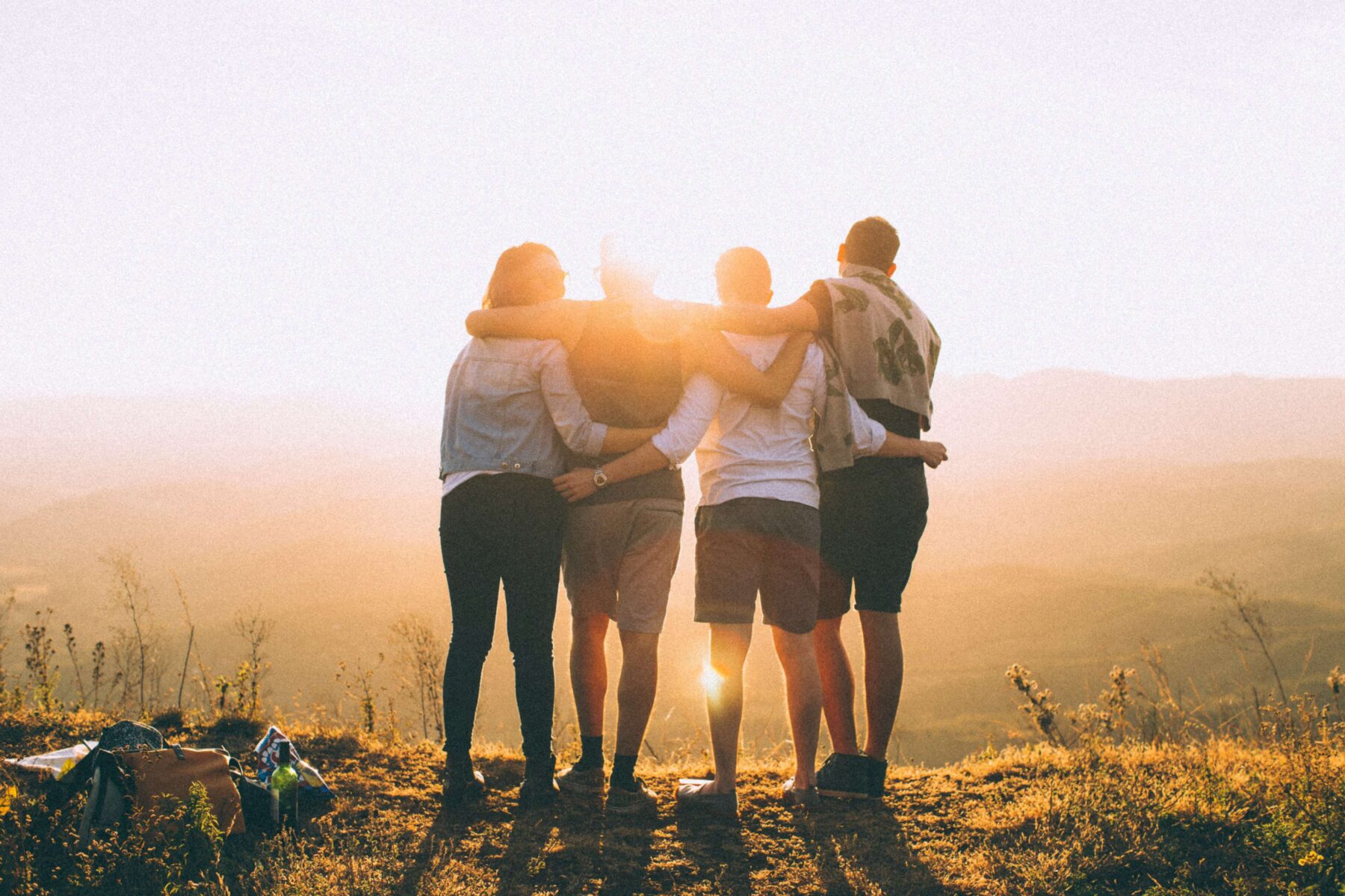 group of friends holding each other in a hug looking at a sunset