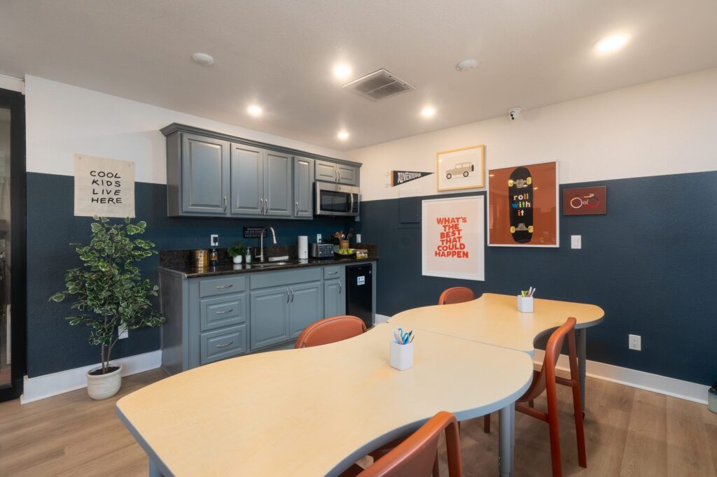 Kids clubhouse with designer lighting, kitchenet, table seating, wood-style flooring, and wall décor