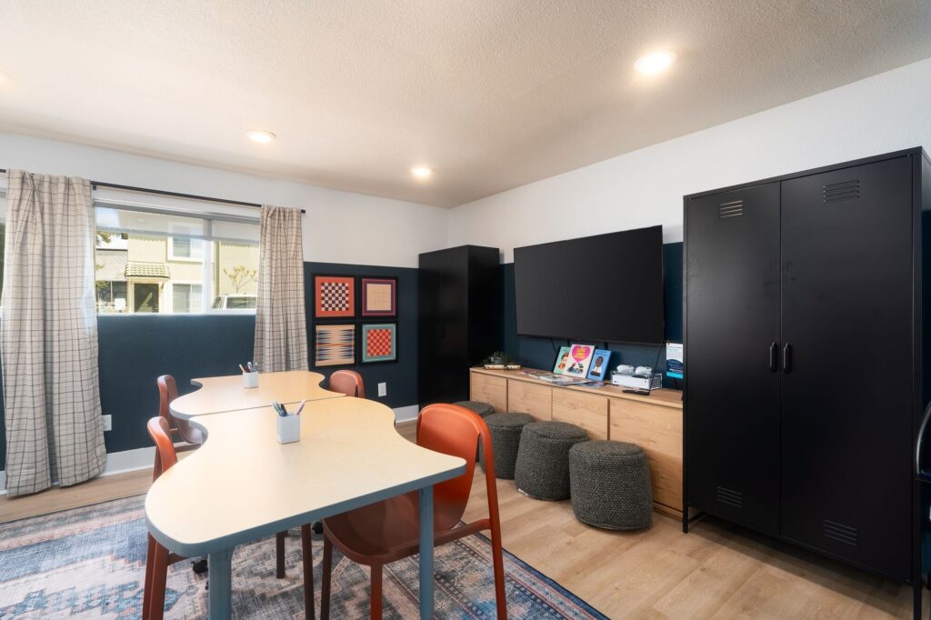 Kids clubhouse with designer lighting, television, table seating, wood-style flooring, and storage lockers